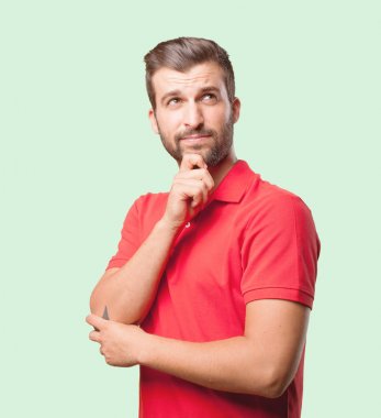Genç yakışıklı gurur düşünme ve kırmızı bir polo gömlek giyen adam. Tek renkli arka planı izole kişi.