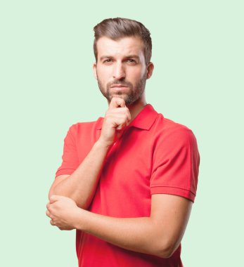 Genç yakışıklı gurur düşünme ve kırmızı bir polo gömlek giyen adam. Tek renkli arka planı izole kişi.