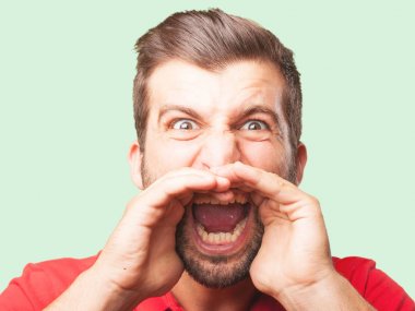 Genç yakışıklı kızgın ifade ve kırmızı bir polo gömlek giymiş bağıran adam. Tek renkli arka planı izole kişi.