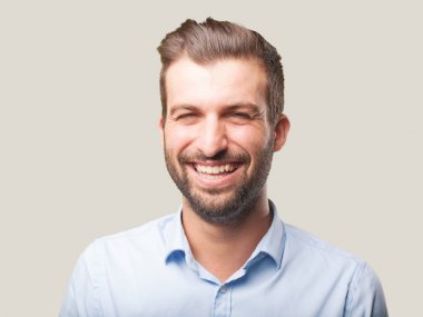 Yakışıklı genç gülümseyen veya mavi t gömlek giymiş gülen adam. Tek renkli arka planı izole kişi.