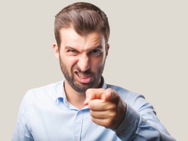 kızgın ifade ve işaretleme açık mavi t gömlek giymiş genç yakışıklı adam. Tek renkli arka planı izole kişi.