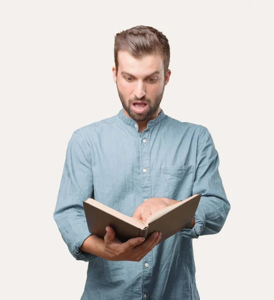 年轻英俊的男子 蓝色牛仔衬衫 拿着一本书 惊讶或快乐的表达 独立于单色背景的人 — 图库照片