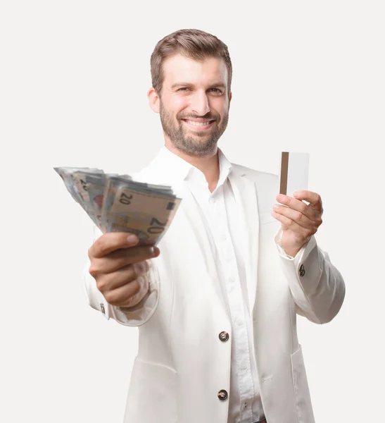 年轻英俊的商人与20欧元钞票和一张信用卡 白色夹克 愉快的表示 独立于单色背景的人 — 图库照片