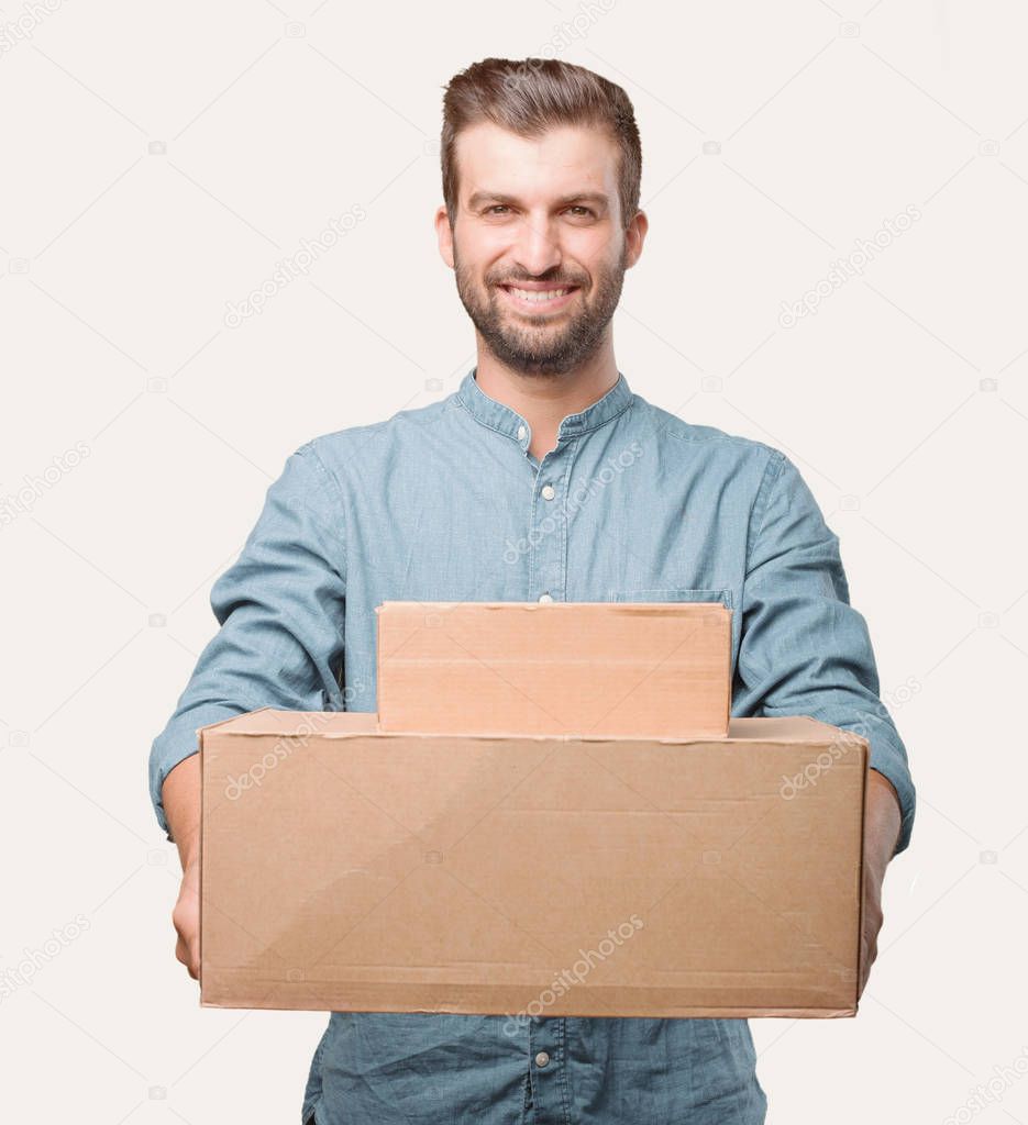 Young handsome man, blue denim shirt, holding a package. Happy expression. Person isolated against monochrome background.