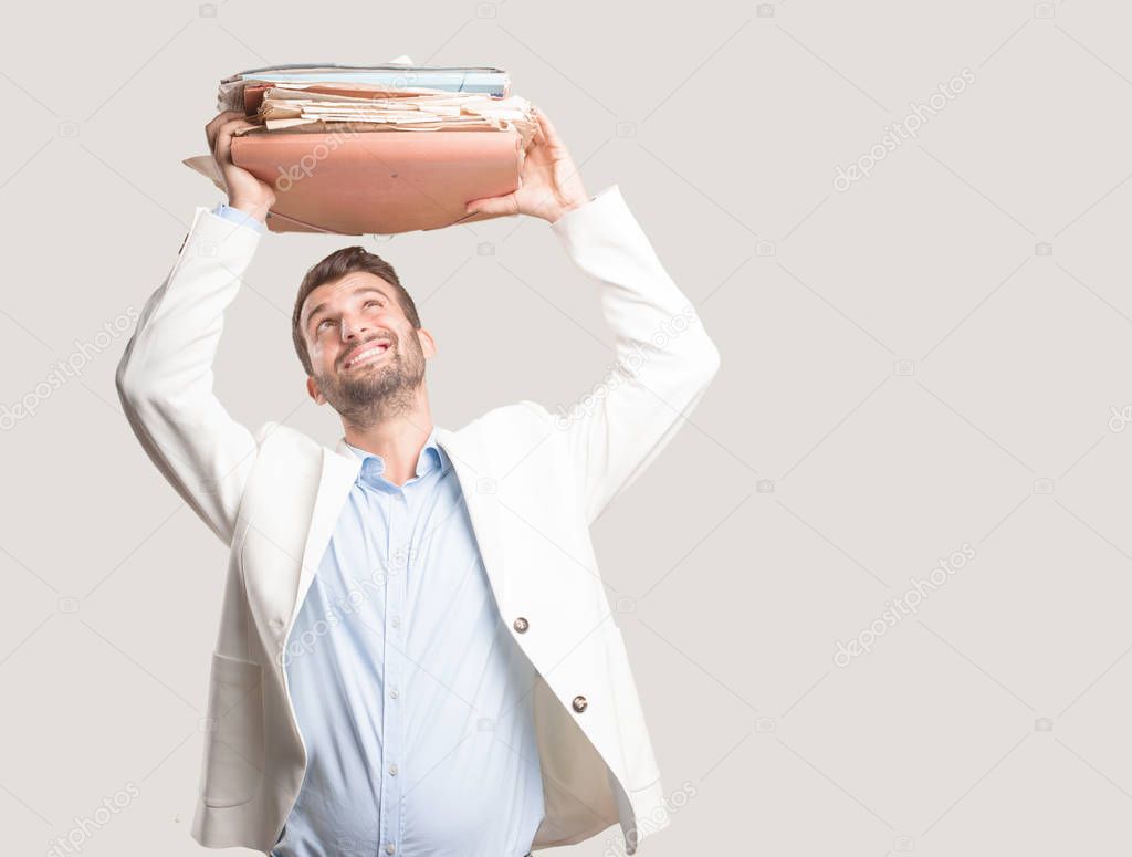 young handsome businessman holding files or a weitht documents tower, white blazer, and bored or disagree expression. Person isolated against monochrome background.