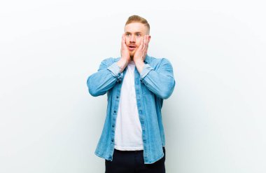 Kot pantolon giyen genç sarışın adam mutlu, heyecanlı ve şaşırmış hissediyordu. İki eli de beyaz arka planda, yana bakıyordu.