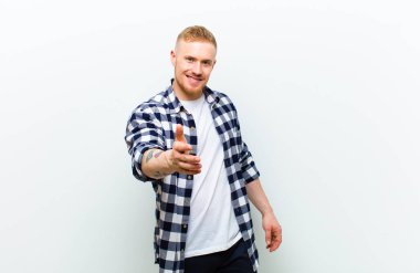 Kare gömlekli, gülümseyen, mutlu görünen, kendine güvenen ve arkadaş canlısı genç sarışın bir adam anlaşma yapmak için el sıkışmayı teklif ediyor.