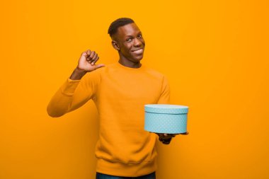 Genç Afro-Amerikan siyah adam turuncu duvara karşı bir hediyeyle