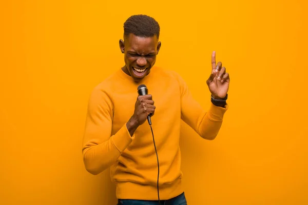 Молодий Афроамериканський Чорний Чоловік Проти Помаранчевої Стіни Мікрофоном — стокове фото