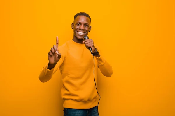 Joven Afroamericano Negro Hombre Contra Pared Naranja Con Micrófono —  Fotos de Stock
