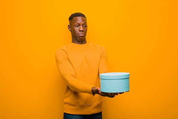 Jovem Negro Afro Americano Contra Parede Laranja Com Presente — Fotografia de Stock