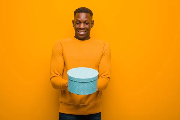 Jovem Negro Afro Americano Contra Parede Laranja Com Presente — Fotografia de Stock