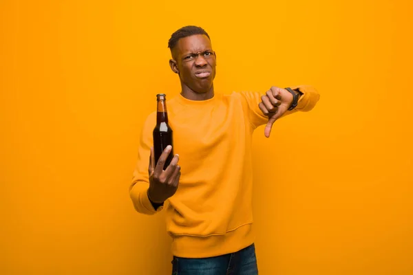 Νεαρός Αφροαμερικάνος Μαύρος Ενάντια Στον Πορτοκαλί Τοίχο Πίνοντας Μπύρα — Φωτογραφία Αρχείου