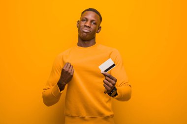 Genç Afrikalı Amerikalı siyahi adam turuncu duvara karşı, para kavramı.