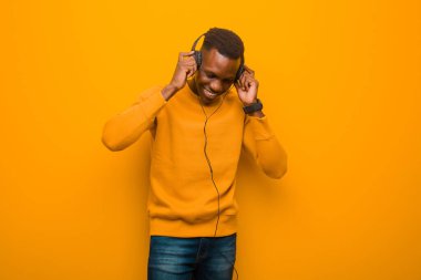 Genç Afro-Amerikan siyah adam turuncu duvarlı ve kulaklıklı