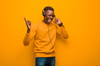 Genç Afro-Amerikan siyah adam turuncu duvarlı ve kulaklıklı