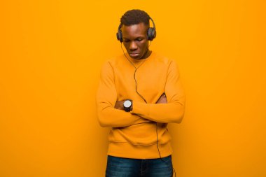 Genç Afro-Amerikan siyah adam turuncu duvarlı ve kulaklıklı