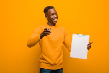 Genç Afro-Amerikan siyahi adam turuncu duvara yaslanmış pankart topluyor.