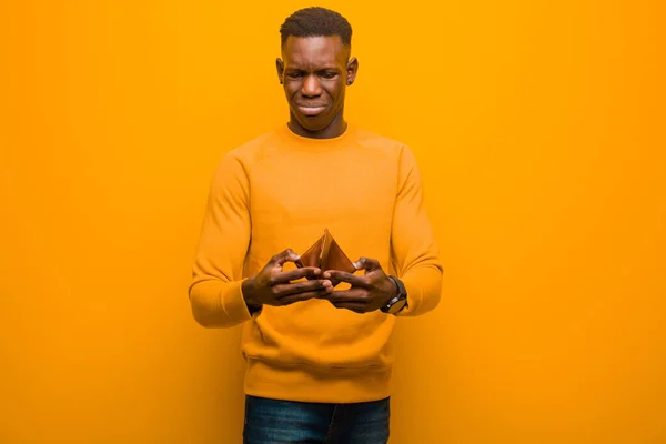 若いアフリカ系アメリカ人黒人男性がオレンジの壁やお金の概念に — ストック写真