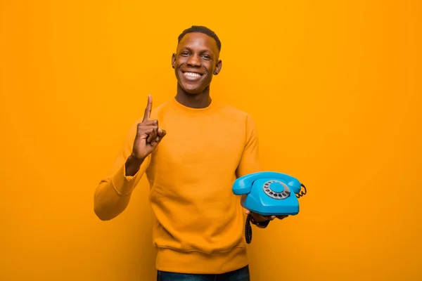 Νεαρός Αφροαμερικάνος Μαύρος Ενάντια Στον Πορτοκαλί Τοίχο Ένα Παλιό Τηλέφωνο — Φωτογραφία Αρχείου