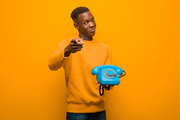 Νεαρός Αφροαμερικάνος Μαύρος Ενάντια Στον Πορτοκαλί Τοίχο Ένα Παλιό Τηλέφωνο — Φωτογραφία Αρχείου