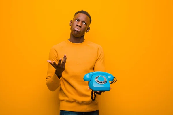 Молодой Африканский Черный Мужчина Против Оранжевой Стены Винтажным Телефоном — стоковое фото
