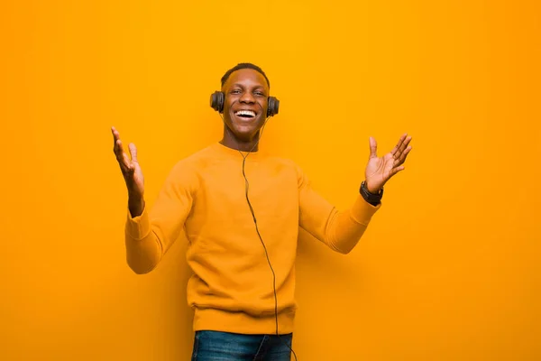 Joven Afroamericano Negro Hombre Contra Pared Naranja Con Auriculares —  Fotos de Stock