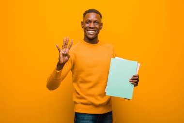 Genç Afro-Amerikan siyahi adam turuncu duvara karşı elinde kitapla