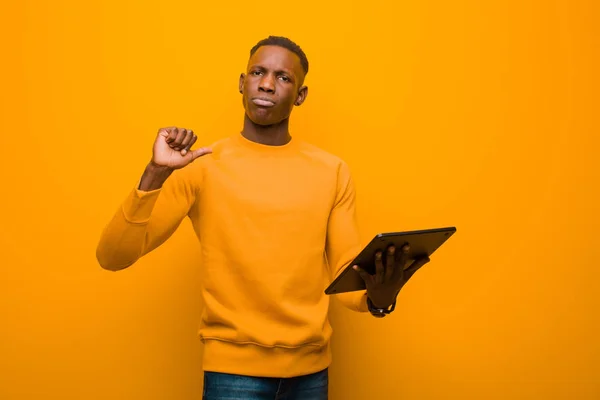 Joven Afroamericano Negro Hombre Contra Pared Naranja Con Una Tableta —  Fotos de Stock