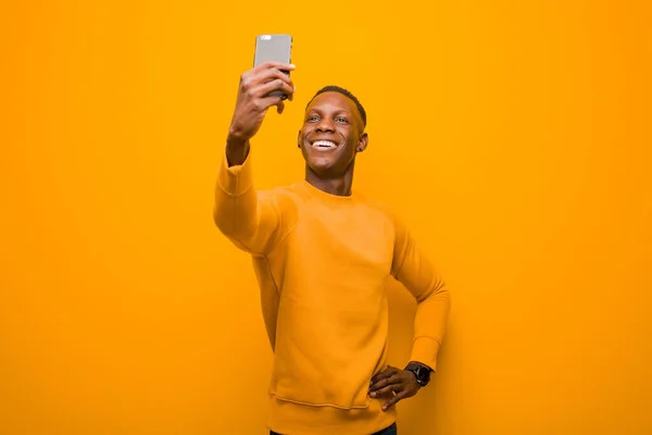 Jovem Negro Afro Americano Contra Parede Laranja Com Telefone Inteligente — Fotografia de Stock