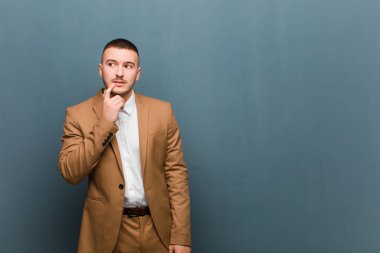 Şaşırmış, gergin, endişeli ya da korkmuş bakışları olan genç yakışıklı bir adam düz arkaplana karşı fotokopi odasına bakıyor.