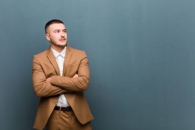 Genç yakışıklı adam şüphe ediyor ya da düşünüyor, dudağını ısırıyor ve kendini güvensiz ve gergin hissediyor, düz duvara karşı boşluğu kopyalamak istiyor.