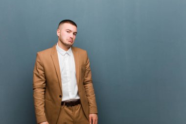 Genç ve yakışıklı iş adamı üzgün ve mızmız görünüyor. Mutsuz bir bakışla ağlıyor. Düz arkaplana karşı olumsuz ve hayal kırıklığına uğramış bir tavırla ağlıyor.