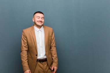 Genç, yakışıklı işadamı şapşal ve komik görünüyor. Şaşı bakışlı, şakacı ve düz arka planda takılıyor.