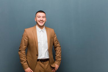 Genç yakışıklı iş adamı mutlu ve hoş bir şekilde şaşırmış görünüyor, düz arkaplan karşısında büyüleyici ve şok olmuş bir ifadeyle heyecanlanıyor.