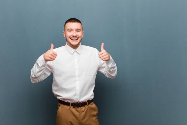 Genç ve yakışıklı iş adamı gülümsüyor. Mutlu, pozitif, kendinden emin ve başarılı görünüyor.