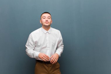 Genç yakışıklı iş adamı dudaklarını birbirine bastırıyor, tatlı, eğlenceli, mutlu, sevimli bir yüz ifadesiyle, düz arkaplana bir öpücük yolluyor.