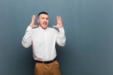 Genç yakışıklı iş adamı elleri havada bağırıyor, öfkeli, sinirli, stresli ve üzgün hissediyor.