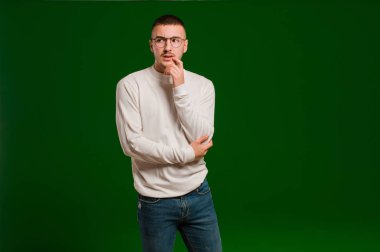 Şaşırmış, gergin, endişeli ya da korkmuş bakışları olan genç yakışıklı bir adam düz arkaplana karşı fotokopi odasına bakıyor.