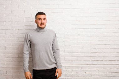 Genç yakışıklı adam kendini cahil, kafası karışmış ve hangi seçeneği seçeceğine karar verememiş, düz duvara karşı sorunu çözmeye çalışıyor.