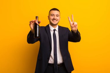 Genç yakışıklı iş adamı arka planda bira içiyor.