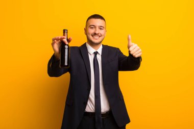 Genç yakışıklı iş adamı arka planda bira içiyor.