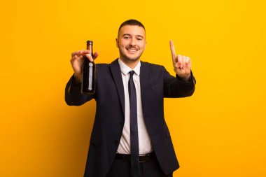 Genç yakışıklı iş adamı arka planda bira içiyor.