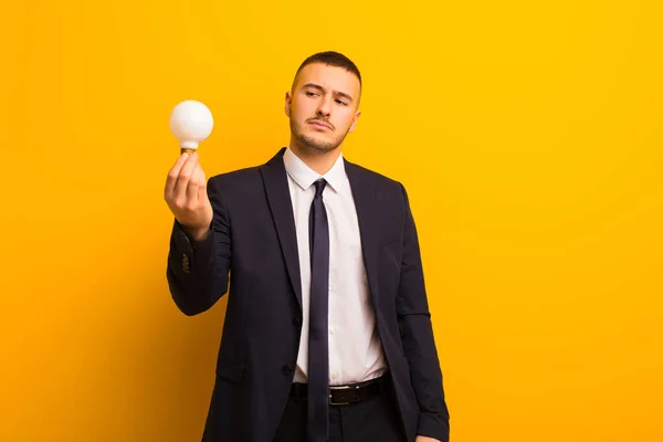 Joven Hombre Negocios Guapo Contra Fondo Plano Con Una Bombilla — Foto de Stock