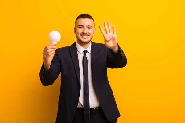 電球を使った平らな背景を持つ若いハンサムなビジネスマン — ストック写真