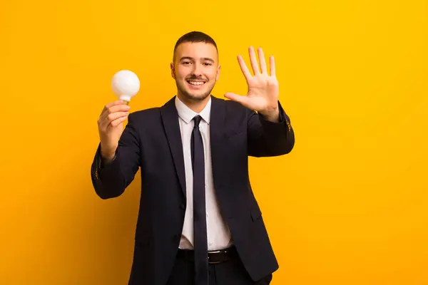 Jonge Knappe Zakenman Tegen Platte Achtergrond Met Een Gloeilamp — Stockfoto