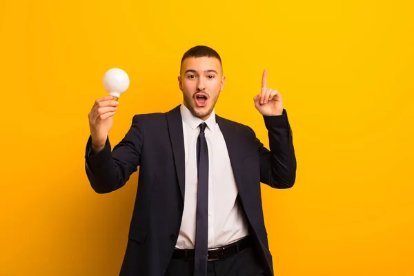 young handsome businessman  against flat background with a light bulb