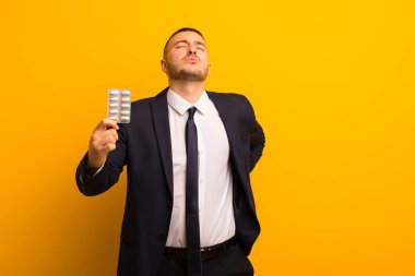 Genç ve yakışıklı iş adamı, ilaç kapsülleriyle arka planda yaşıyor.