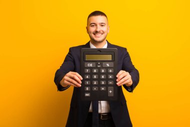 Genç ve yakışıklı iş adamı arka planda hesap makinesiyle