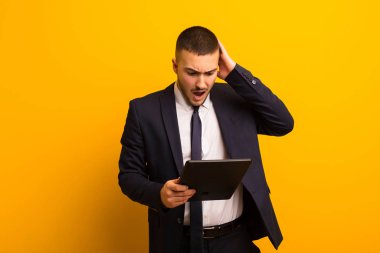 Genç yakışıklı iş adamı tabletle arka planda yaşıyor.